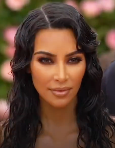 Kim Kardashian mit langen it Gel in Wellen gelegten Haaren.