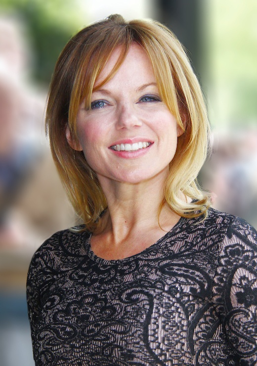 Geri Halliwell mit schulterlangen rotblonden Haaren. Sie schaut lächelnd in die Kamera.