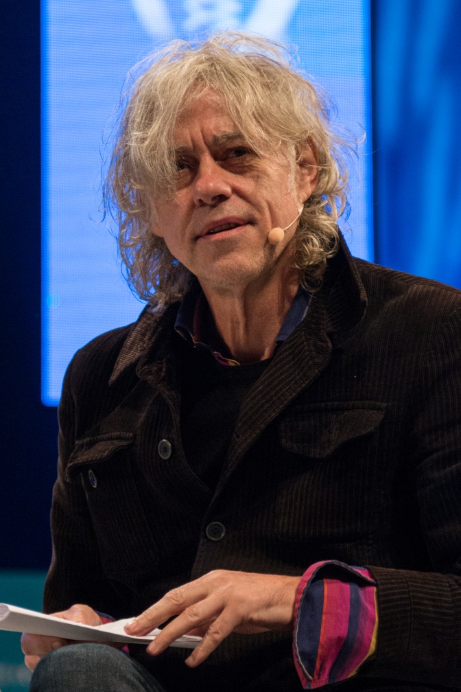 Bob Geldof mit grauen gewellten Haaren in schwarzer Kleidung.