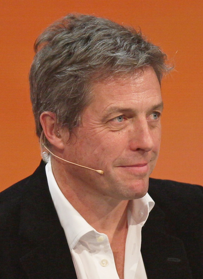 Hugh Grant in Anzug und Hemd mit einem Ansteckmikro.