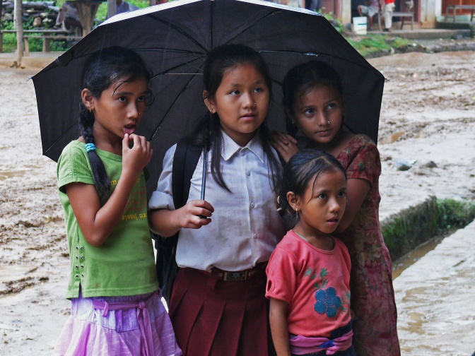 4 Mädchen unter einem Regen-Schirm