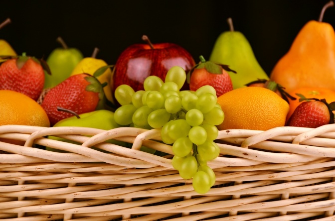 Ein Korb mit Obst: Äpfel, Trauben, Erdbeeren, Birnen und Orangen