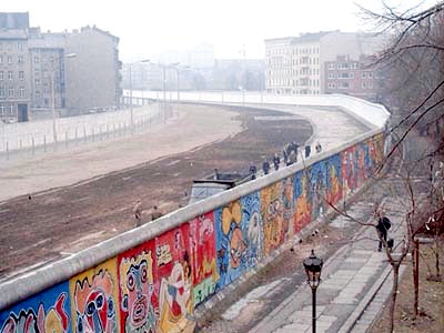 Die Berliner Mauer, von der Westseite mit Graffitti-Bemalung, im Hintergrund Wohnhäuser