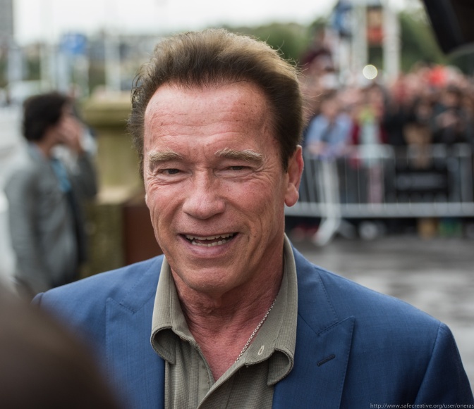 Arnold Schwarzenegger in einem aufgeknöpften Hemd und einem Sakko.