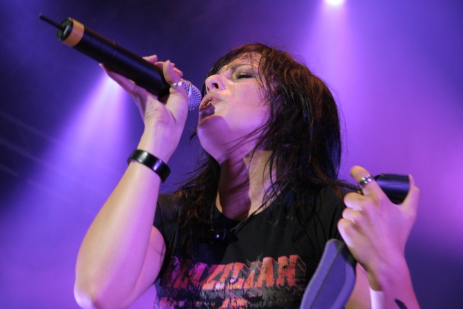 Stefanie Kloß singt in ein Mikrophon, die Bühne ist farbig beleuchtet.