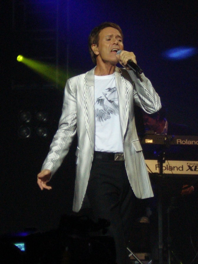 Cliff Richard auf der Bühne: Er singt in ein Mikrophon.