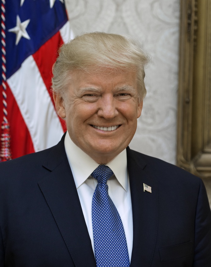 Donald Trump lächelnd in Anzug und Krawatte vor einer amerikanischen Flagge