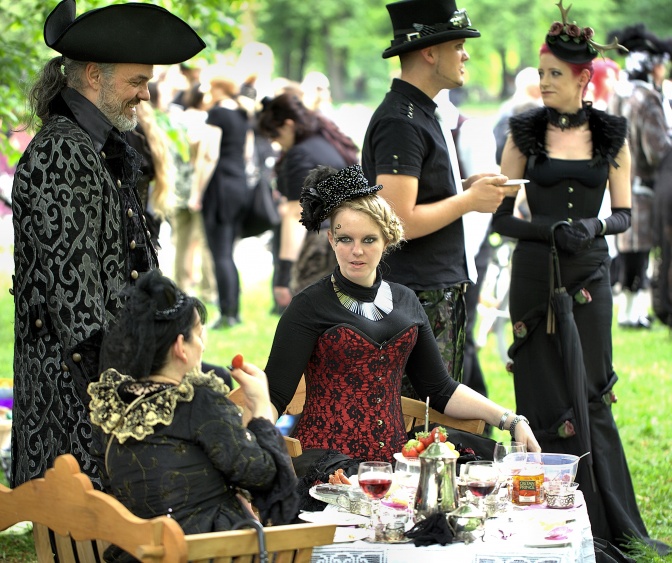 Teilnehmer und Teilnehmerinnen in schwarzen, historisch anmutenden Kostümen bei einem Picknick im Rahmen des Wave-Gotik-Treffens