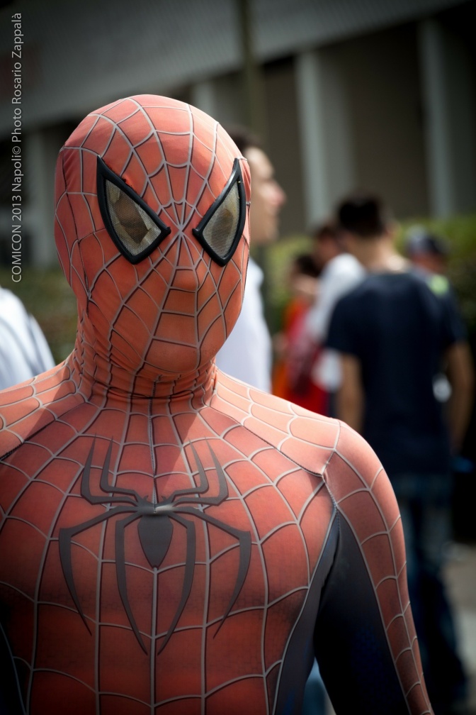 Ein Mann in einem Spider-Man-Kostüm, im Hintergrund eine Menschengruppe.