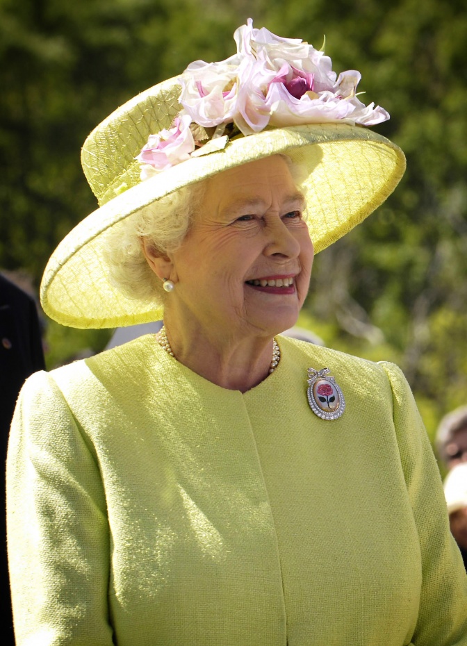 Queen Elisabeth die Zweite in einem Kostüm mit passendem Blumenhut.