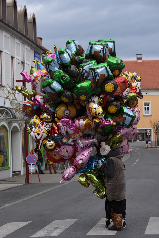 Ein Ballon-Verkäufer mit einem Strauß an Helium-Ballons aus metallischer Folie