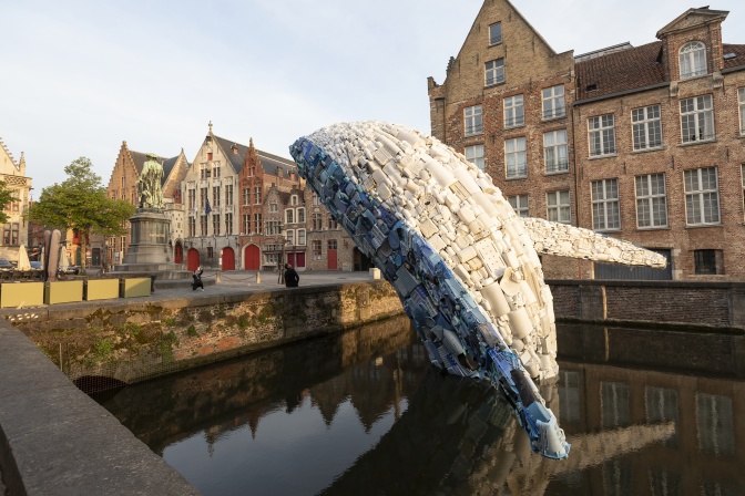 Eine Wal-Skulptur aus Plastikmüll in weiß und blau. Der untere Teil der Skulptur befindet sich im Wasser, der Wal scheint zu springen.