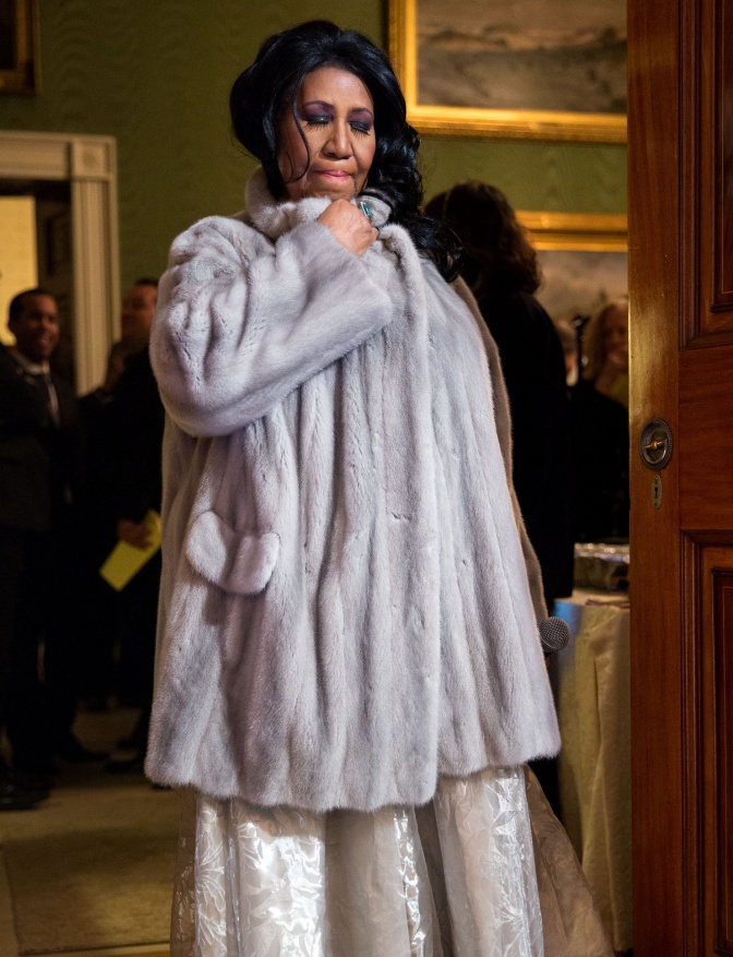 Aretha Franklin in einem grauen Pelzmantel und mit geschlossenen Augen