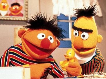 Ernie und Bert stehen nebeneinander. Ernie hält sein Quietscheentchen in der Hand.