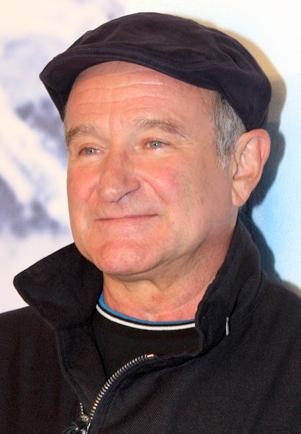 Robin Williams mit einer schwatze Schiebermütze. Seine Jacke ist auch schwarz, der Kragen ist hochgestellt.