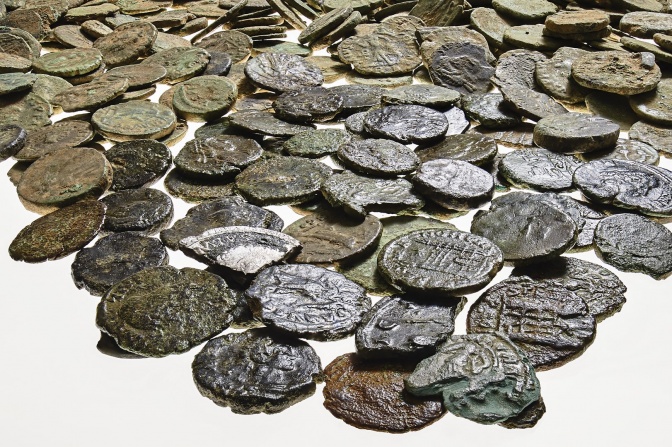 Viele alte Kupfermünzen legen neben- und übereinander. Sie sind alt, aber gut erhalten. Manche sind nur in Teilen erhalten.