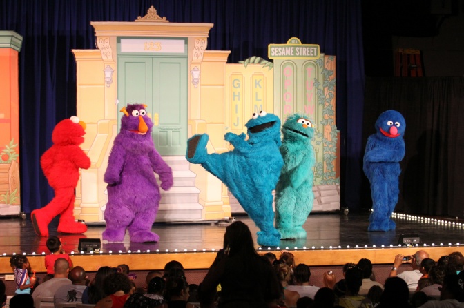 4 verschiedenfarbige Monster aus der Sesamstraße auf der Bühne.