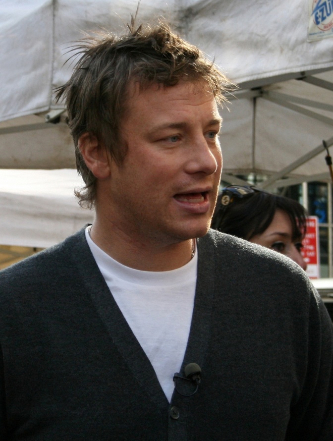 Jamie Oliver in einem Pullover mit V-Ausschnitt und kurzen blonden Haaren.