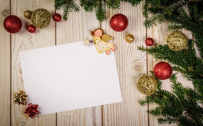 Eine unbeschriebene Weihnachtskarte. Rechts daneben sind Tannenzweige und Weihnachtskugeln zu sehen.
