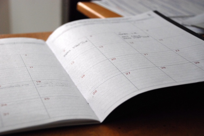 Ein aufgeschlagener Kalender in Buchform mit handschriftlichen Eintragungen.