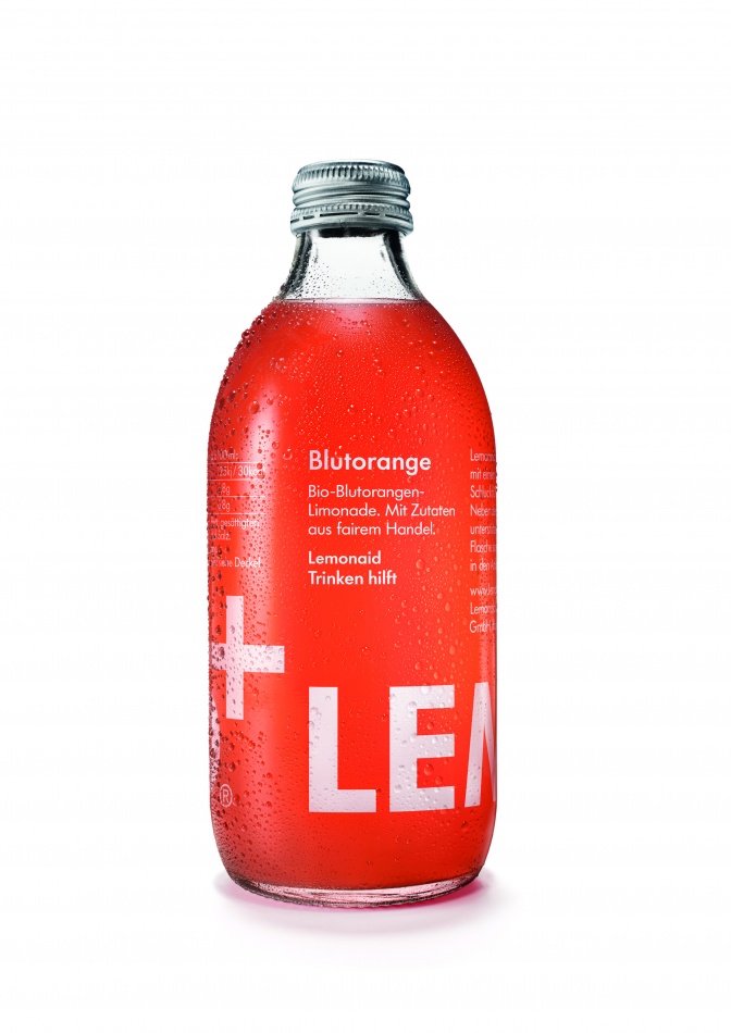 Eine durchsichtige Glasflasche mit Schraubverschluss. Die Flasche ist mit einer rot-orangenen Limonade gefüllt. Darauf steht der Schriftzug LEMONAID in Großbuchstaben.