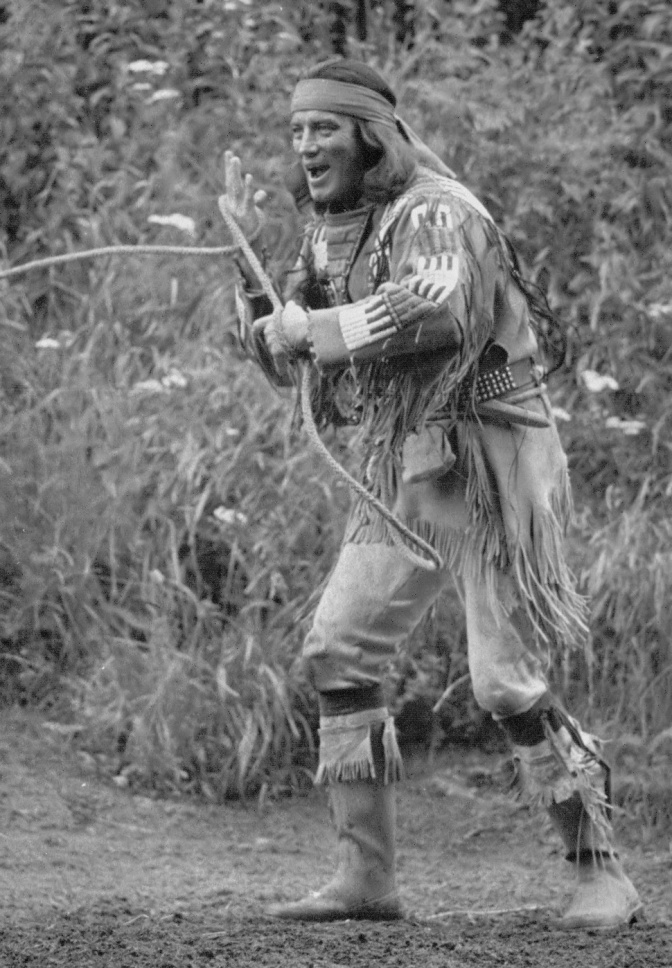 Ein schwarz-weiß-Foto von Pierre Brice im Indianer-Kostüm mit Pfeil und Bogen.