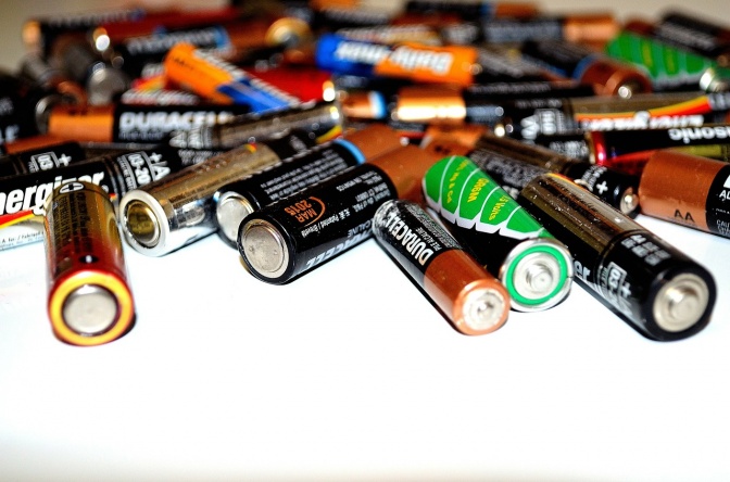 Batterien verschiedener Marken liegen neben- und übereinander auf einer weißen Fläche.