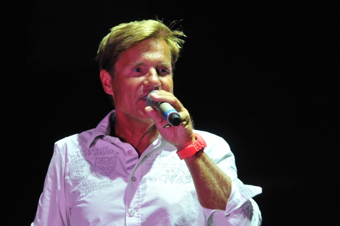 Dieter Bohlen trägt ein weißes Hemd mit aufgekrempelten Ärmeln und spricht in ein Mikrophon.