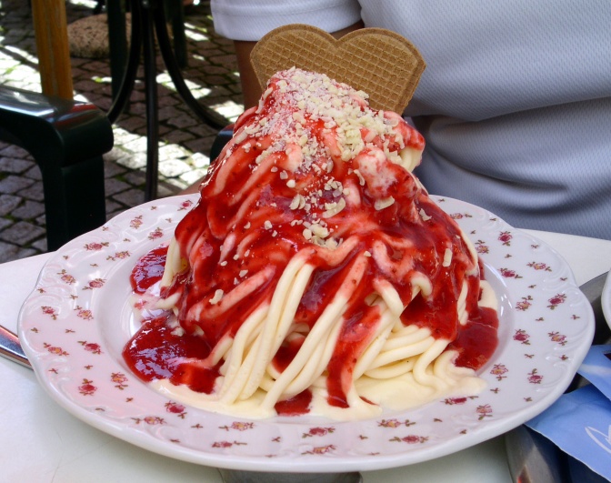 Ein Portion Spaghettieis auf einem gemusterten Teller.