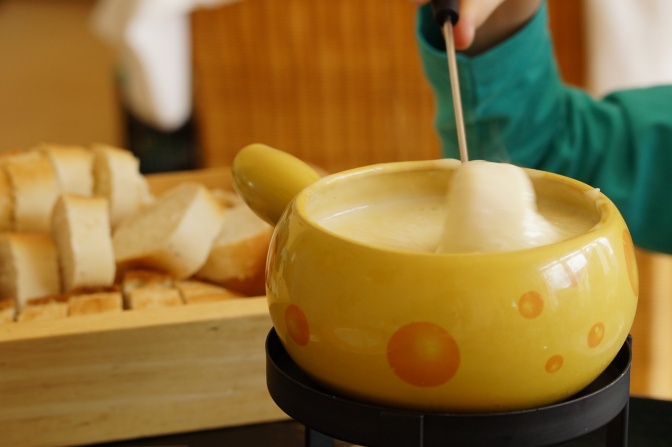 Käse-Fondue in einem Keramik-Topf, der auch auassieht wie ein Käse.