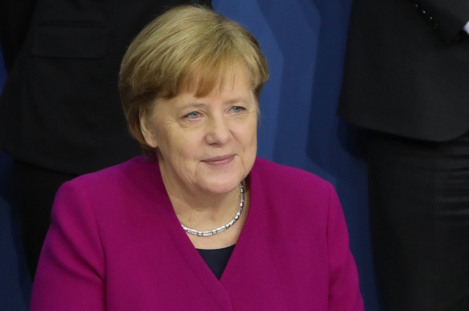 Angela Merkel in einem Hosenanzug und mit Perlenkette.
