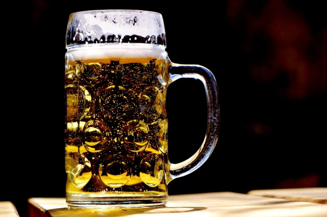 Ein gefüllter Bierkrug mit Schaumkrone vor schwarzem Hintergrund