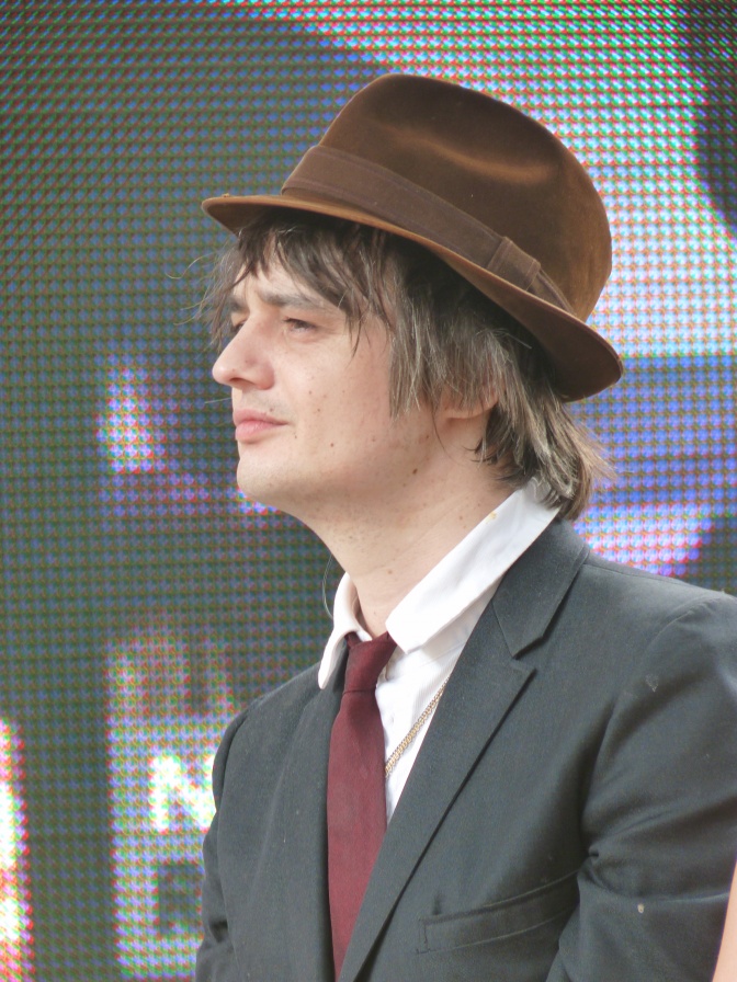 Pete Doherty im Profil fotografiert. Er trägt Anzug und Krawatte und einen Hut.
