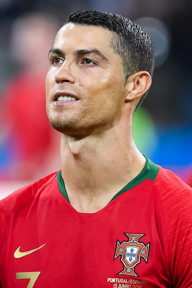 Cristiano Ronaldo mit kurzen schwarzen Haaren. Er trägt ein Fußballtrikot mit verschiedenen Markenlogos.