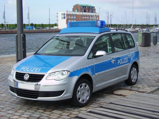 Ein Polizeiauto steht geparkt auf einem Holzsteg. Im Hintergrund sieht man Wasser.