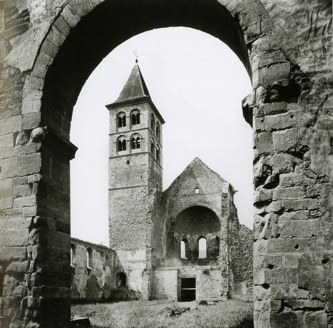 Ein schwarz-weiß Foto einer Klosterruine. Man sieht einen Torbogen und einen Glockenturm.