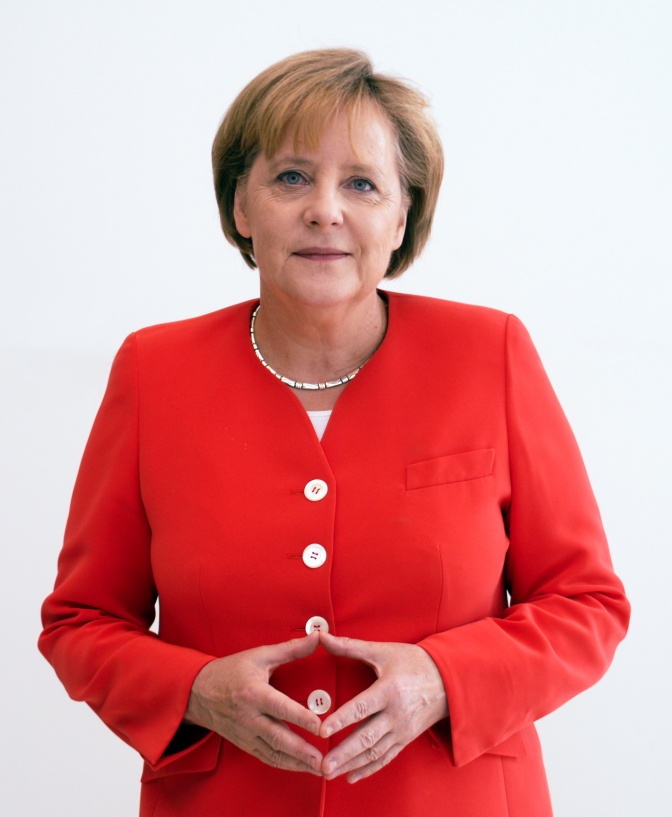 Angela Merkel legt die Hände ineinander, sodass der Zwischenraum zwischen ihren Fingern eine Raute bildet.