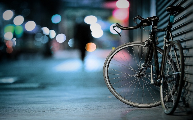 Ein Herrenrad steht nachts an eine Bretterwand gelehnt.