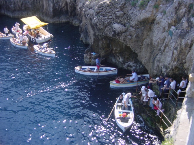 Mehrere kleine Boote am Eingang der im Meer liegenden Felsgrotte