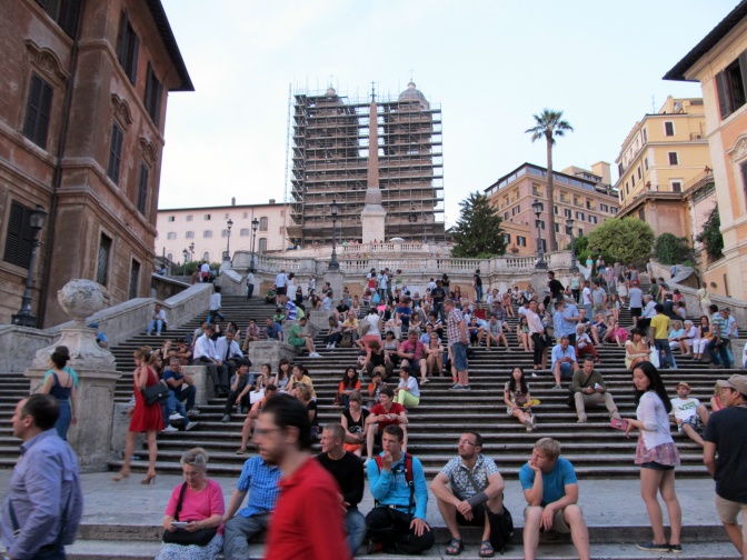 Viele Menschen sitzen in sommerlicher Kleidung auf der spanischen Treppe