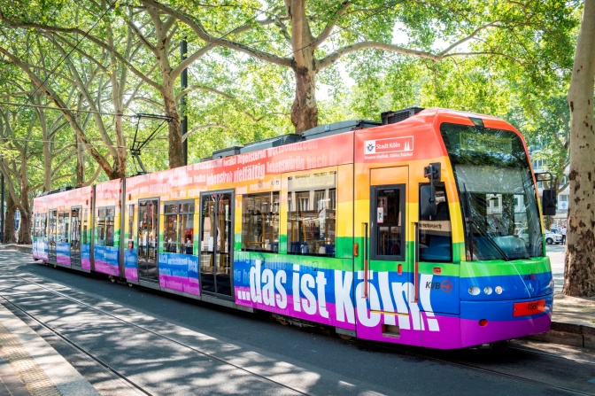 Eine in Regenbogenfarben gestreifte Bahn mit der Aufschrift ...das ist Köln.