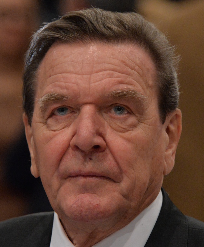 Gerhard Schröder mit braunen Haaren und faltigem Gesicht. Er trägt Anzug und Sakko.