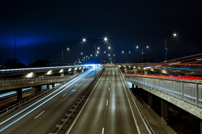Eine Autobahn bei Nacht. Man sieht rote Rücklichter fahrender Autos.