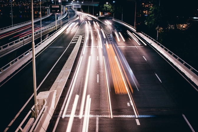 Eine Autobahn bei Nacht. Die Lichter der Autos verschwimmen zu. Linien aus Licht.