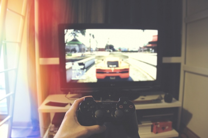 Ein Mensch spielt mithilfe eines Controllers ein Autorennspiel auf einer Spielekonsole
