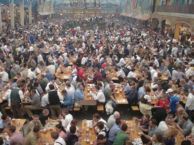 Viele Menschen sitzen auf Bierbänken und trinken Bier. Viele von ihnen tragen Tracht.