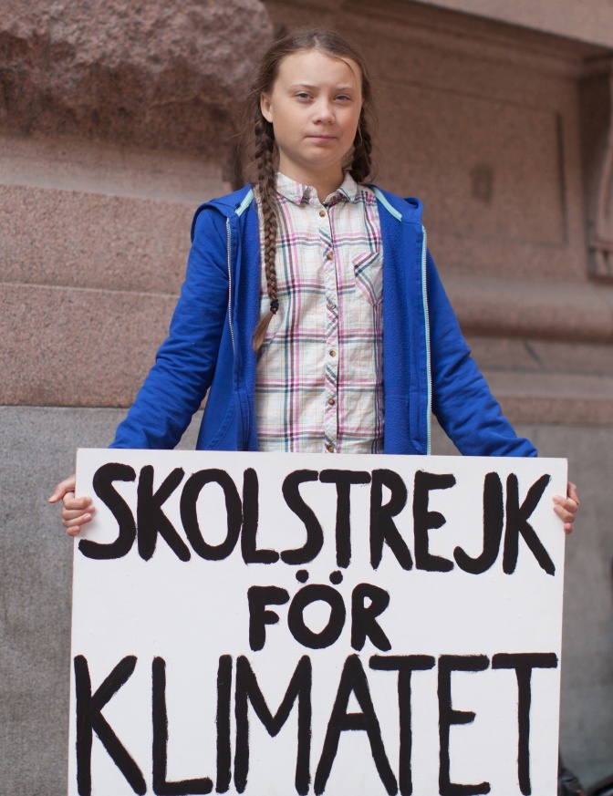 Greta Thunberg mit einem Protest-Schild mit schwedischer Schrift. Übersetzt heißt der Schriftzug: Schulstreik fürs Klima.