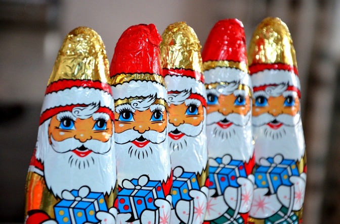 5 Weihnachtsmänner aus Schokolade stehen in einer Reihe nebeneinander.