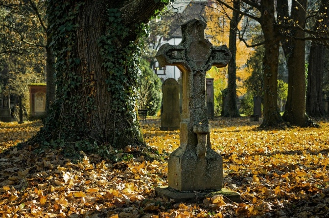 Ein altes Steinkreuz auf einem herbstlichen Friedhof