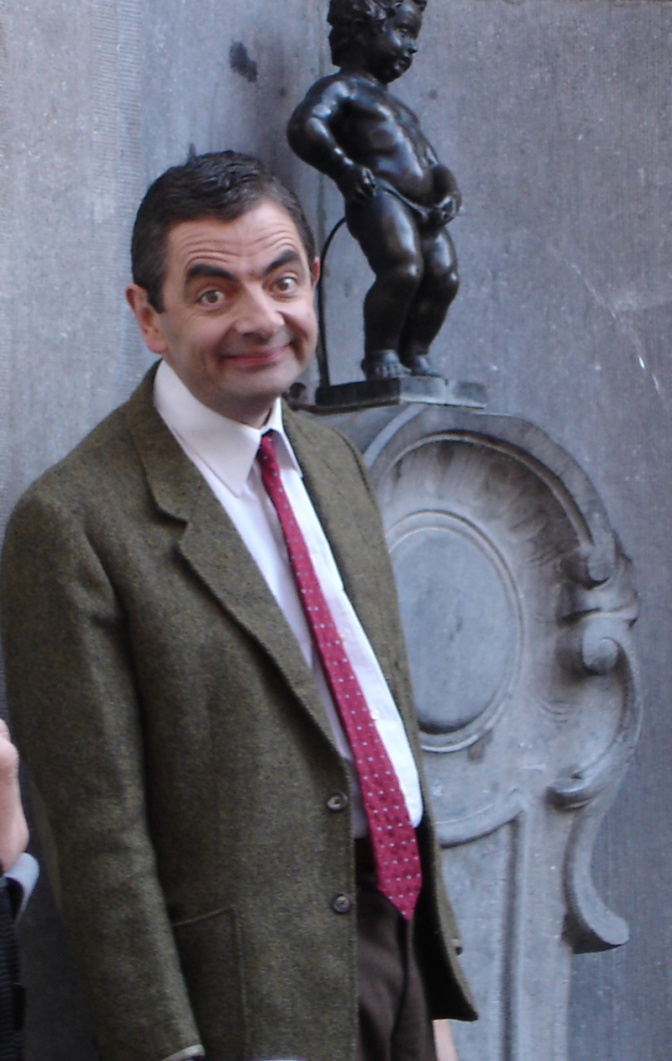 Rowan Atkinson trägt Anzug und Krawatte und zieht eine Grimasse.